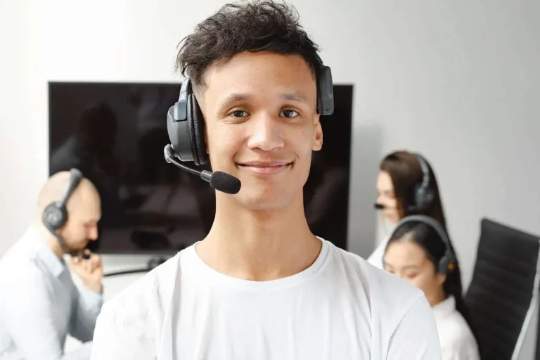 A professional call center agent wearing a headset, smiling while assisting a customer