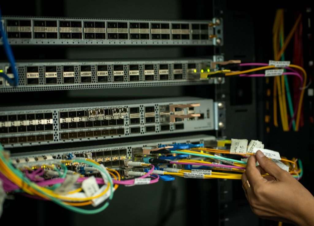 A network technician managing fiber optic cables in a server room, representing the expansion of high-speed fiber broadband infrastructure