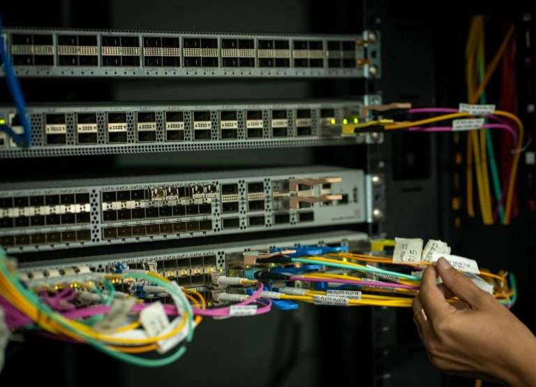 A network technician managing fiber optic cables in a server room, representing the expansion of high-speed fiber broadband infrastructure