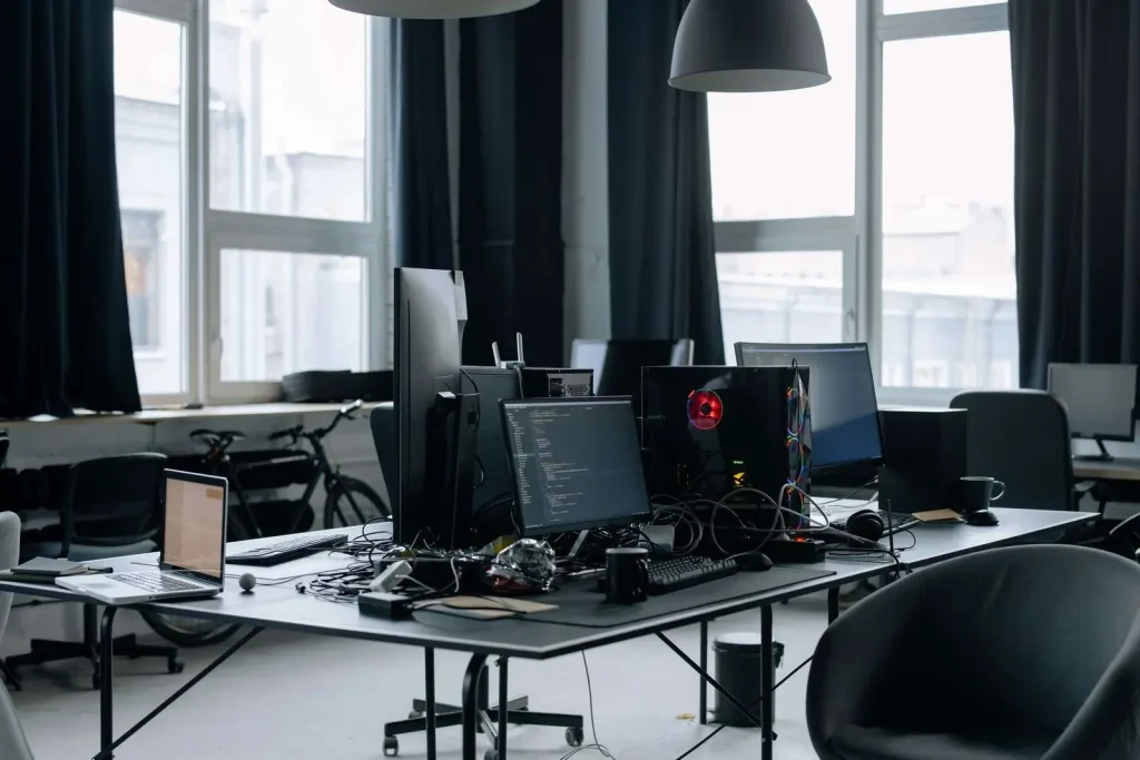 Empty modern open office with desktop computers and monitors on rows of desks