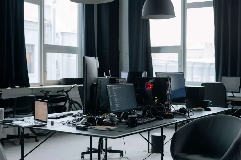 Empty modern open office with desktop computers and monitors on rows of desks