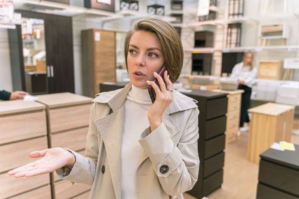 Store manager talking on a mobile phone inside a furniture showroom, representing multi-location business communications