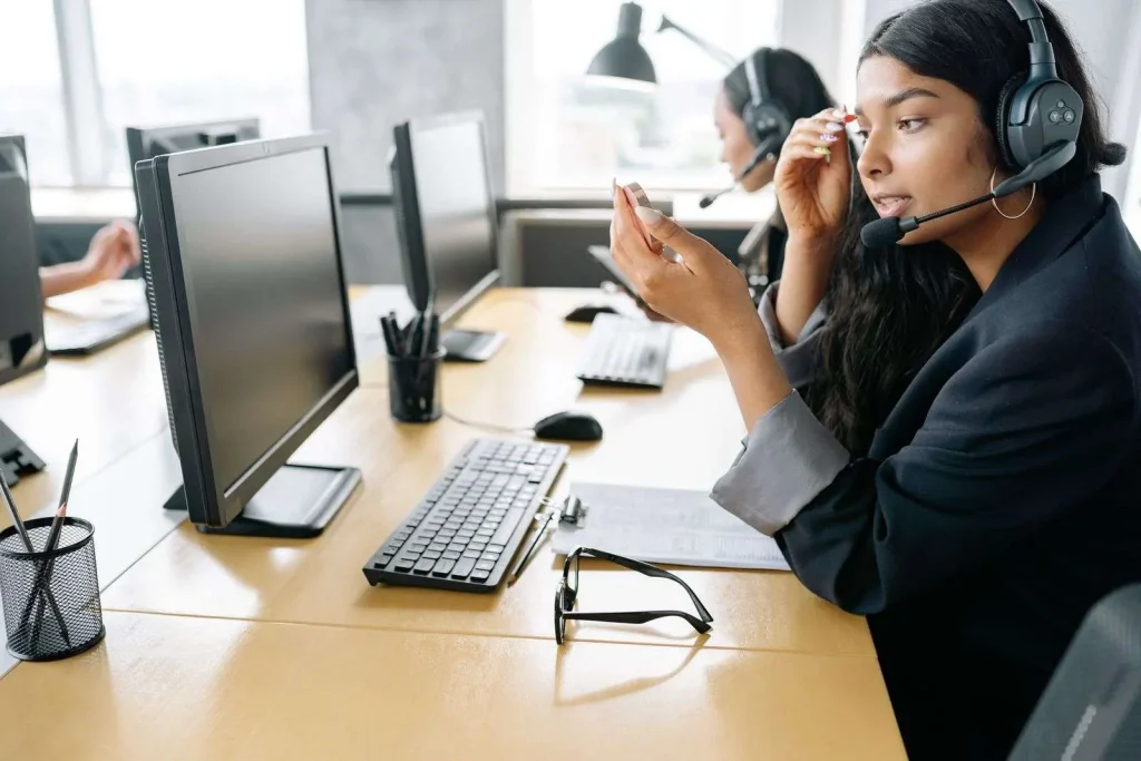 Customer support agent wearing a headset working at a computer in a modern office contact center