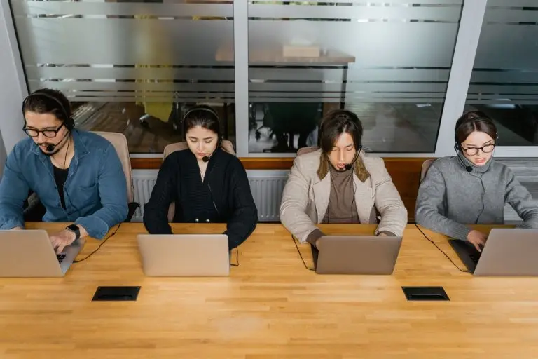 Outbound sales team wearing headsets working on laptops in a modern office, representing power dialer calling