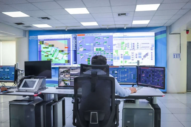 Wall of monitoring screens in a network operations center showing circuit health graphs, latency trends and device status alerts