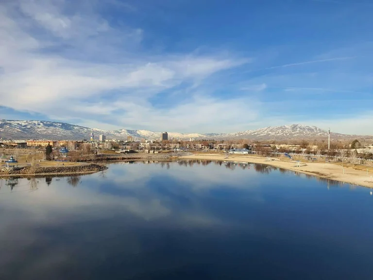 Reno, Nevada skyline reflected in a calm lake with the snow-capped Sierra Nevada mountains behind it