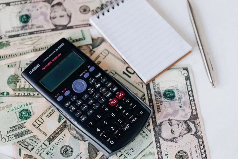 Calculator, notepad, and cash on a desk representing business budget planning for VoIP phone system costs