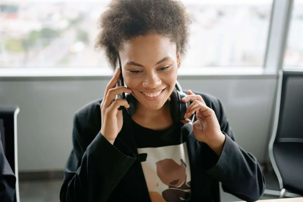 Business desk phone and headset beside a notepad with a handwritten phone menu script outline, ready for recording auto attendant greetings